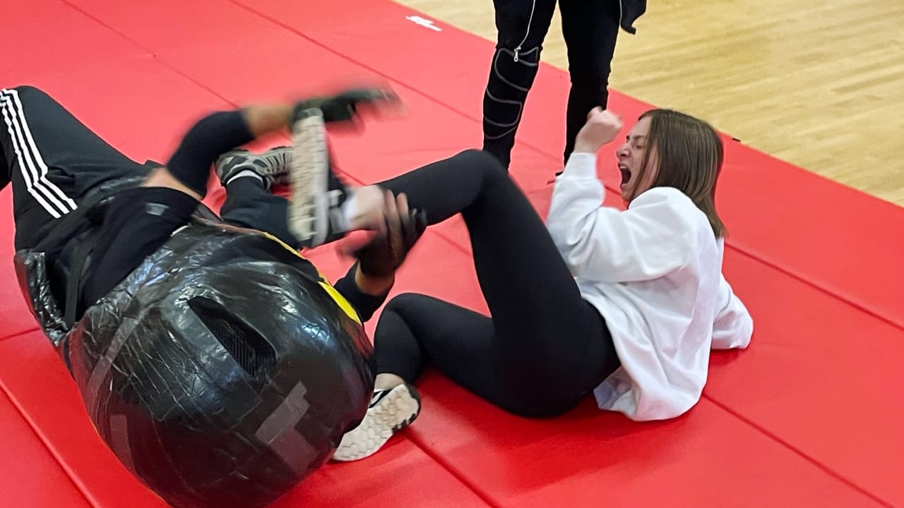 ESD student fighting an instructor dressed as an assailant on a mat in class.