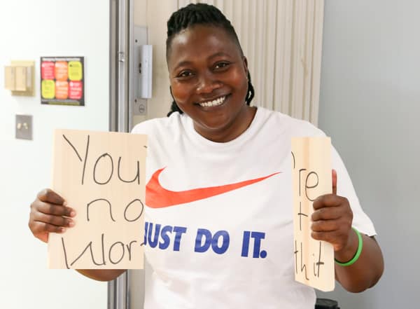 Smiling woman holding a broken board with the words "you're not worth it" written on it. She smashed it!